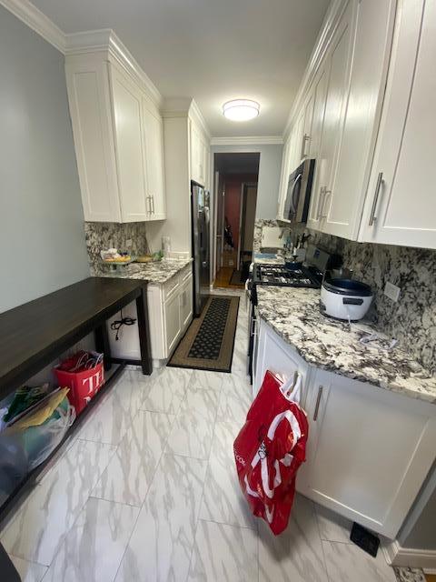 35-21 81st St Unit 1B, Jackson Heights, NY 11372 - kitchen featuring gas range, stainless steel microwave, freestanding refrigerator, light marble finish floors, and tasteful backsplash
