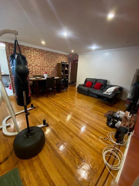 35-21 81st St Unit 1B, Jackson Heights, NY 11372 - living room with wood finished floors, wallpapered walls, and crown molding