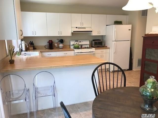 87 Marjorie Ct, Manhasset, NY 11030 - kitchen with white appliances, ventilation hood, light countertops, a peninsula, and white cabinets