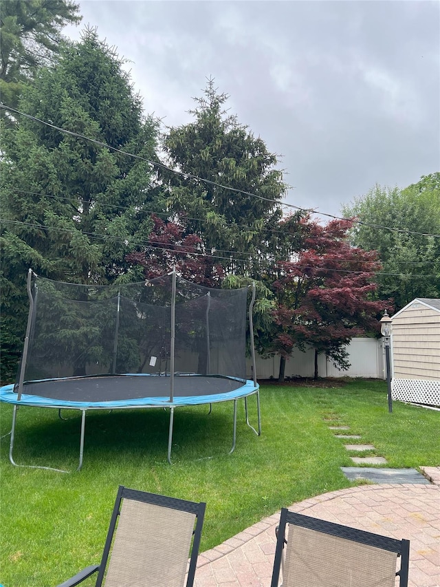 18 Sherwood Ln, Roslyn Heights, NY 11577 - view of grassy yard featuring a trampoline, a patio, and a storage unit