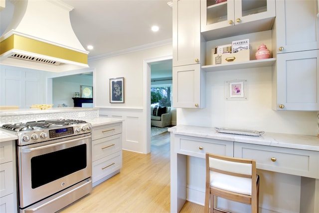 30 Prescott St, Garden City, NY 11530 - kitchen with stainless steel gas range oven, premium range hood, crown molding, light wood-style flooring, and glass insert cabinets
