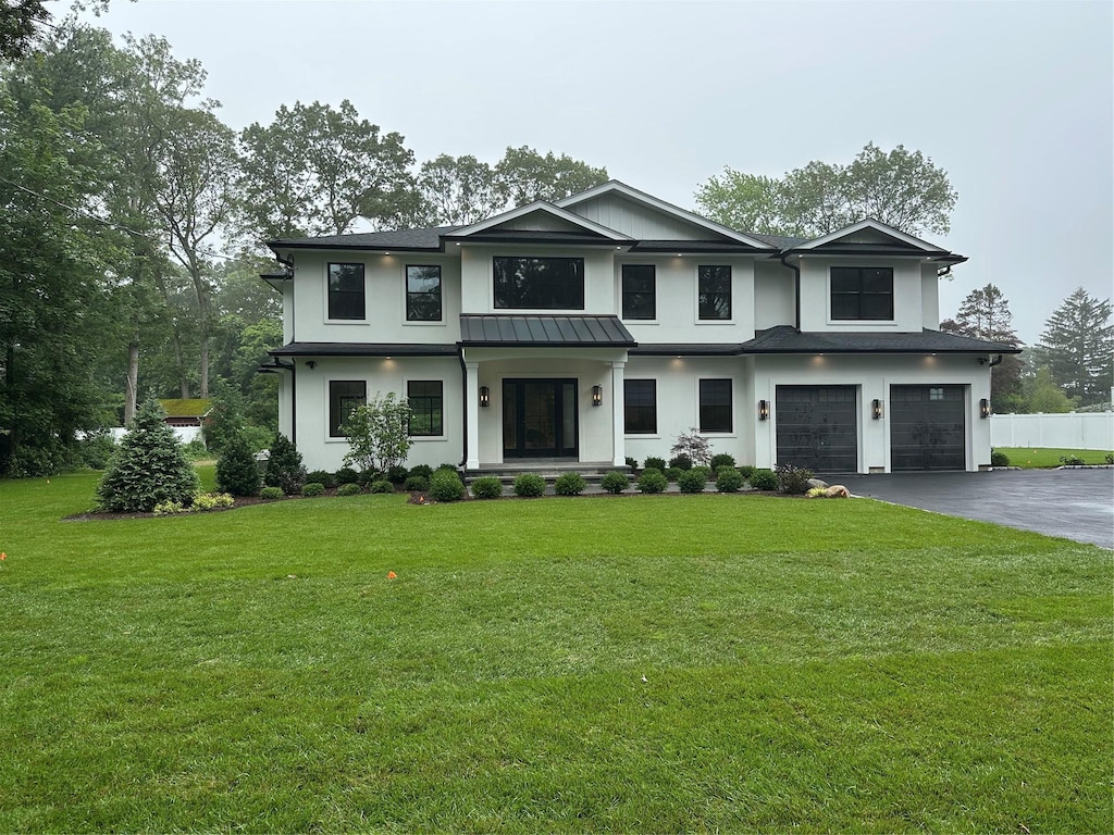 352 Cold Spring Rd, Syosset, NY 11791 - view of front of house featuring an attached garage, asphalt driveway, stucco siding, a standing seam roof, and a metal roof