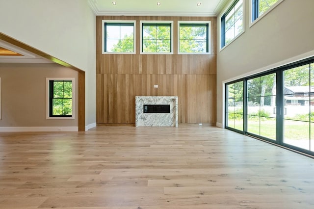 352 Cold Spring Rd, Syosset, NY 11791 - unfurnished living room featuring a towering ceiling, crown molding, a premium fireplace, and light wood finished floors