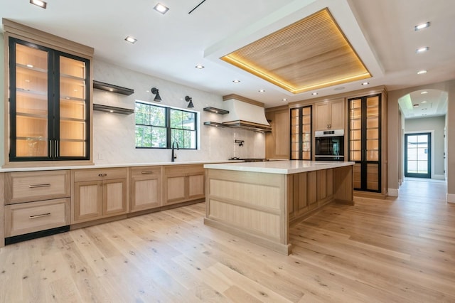 352 Cold Spring Rd, Syosset, NY 11791 - kitchen featuring a raised ceiling, light brown cabinetry, arched walkways, light wood-type flooring, and healthy amount of natural light