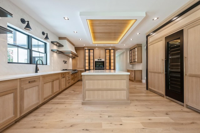 352 Cold Spring Rd, Syosset, NY 11791 - kitchen featuring light brown cabinetry, a tray ceiling, beverage cooler, light wood-style flooring, and recessed lighting