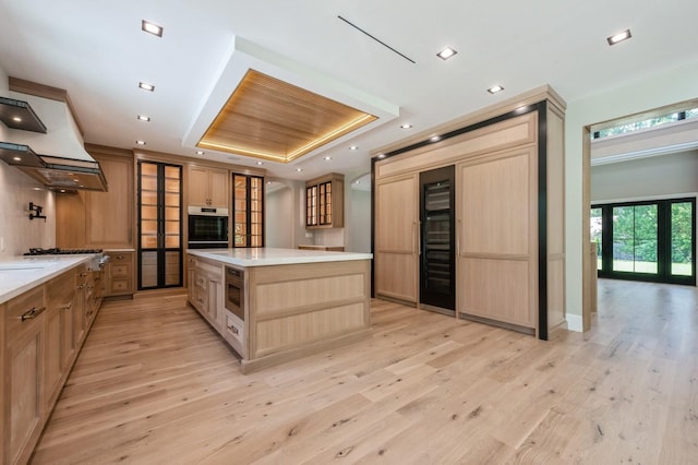 352 Cold Spring Rd, Syosset, NY 11791 - kitchen with appliances with stainless steel finishes, a tray ceiling, light brown cabinets, light wood finished floors, and light countertops