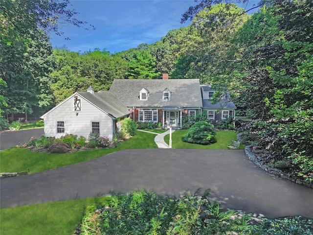 353 Split Rock Rd, Syosset, NY 11791 - cape cod house with a chimney, a front yard, and a forest view