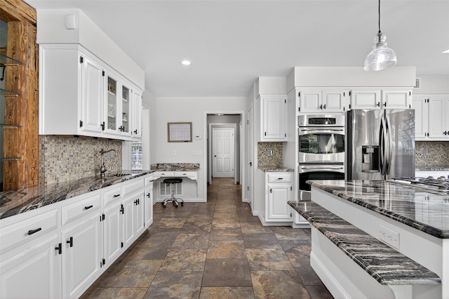 353 Split Rock Rd, Syosset, NY 11791 - kitchen with stainless steel appliances, decorative backsplash, dark stone counters, glass insert cabinets, and white cabinetry