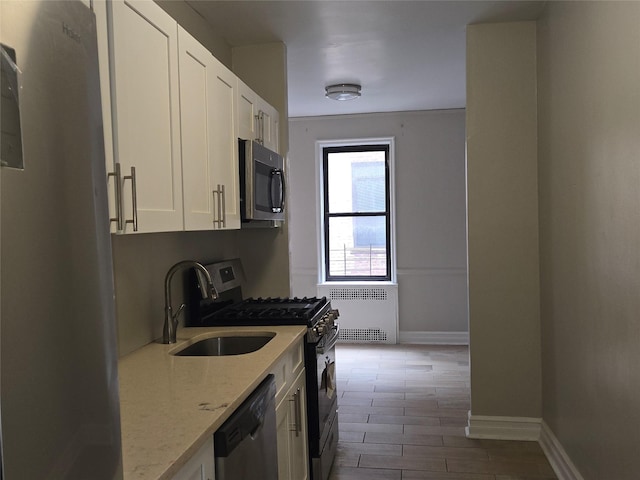 55 E 190th St Unit 45, Bronx, NY 10468 - kitchen featuring stainless steel appliances, radiator, white cabinets, light stone countertops, and wood finished floors