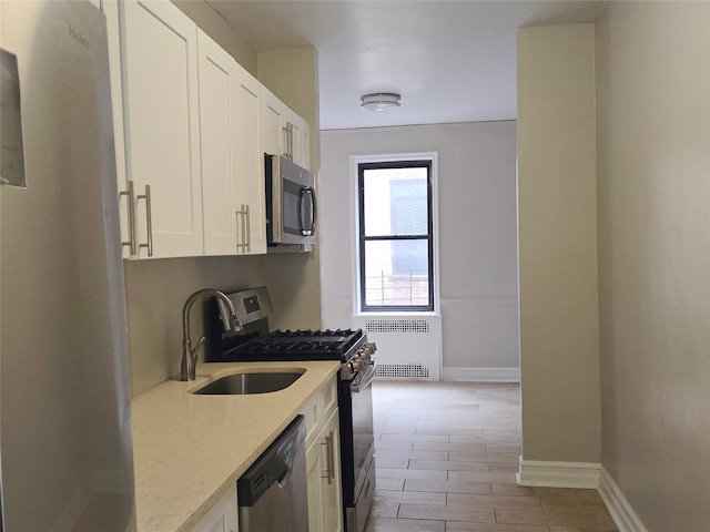 55 E 190th St Unit 45, Bronx, NY 10468 - kitchen with appliances with stainless steel finishes, radiator, white cabinetry, and light stone counters