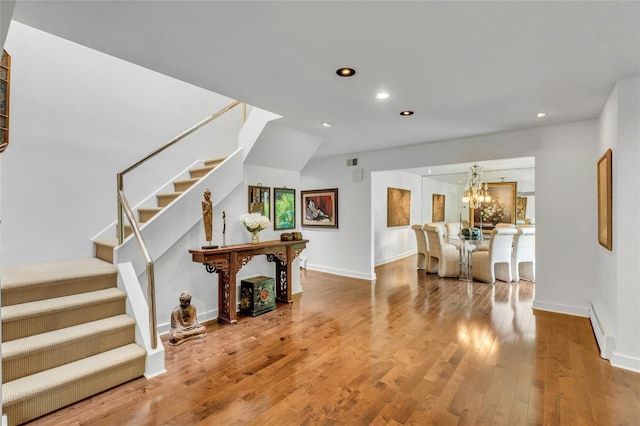 74 Woods Dr, Roslyn, NY 11576 - living room featuring baseboard heating, stairs, recessed lighting, wood finished floors, and a chandelier