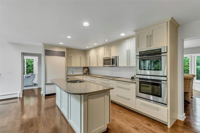74 Woods Dr, Roslyn, NY 11576 - kitchen with appliances with stainless steel finishes, light stone countertops, an island with sink, light wood-style flooring, and recessed lighting