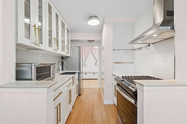 102-30 66th Rd Unit 1G, Forest Hills, NY 11375 - kitchen featuring wall chimney exhaust hood, stainless steel gas range oven, decorative backsplash, light wood-style floors, and light countertops