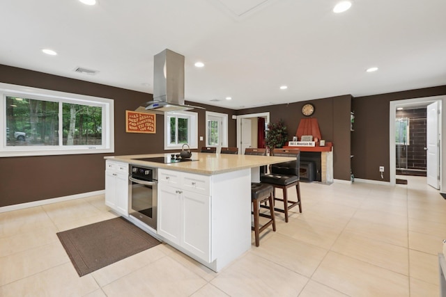 160 S Mountain Rd, New City, NY 10956 - kitchen featuring stainless steel oven, island exhaust hood, white cabinetry, a kitchen bar, and healthy amount of natural light