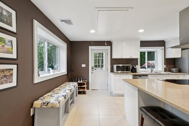 160 S Mountain Rd, New City, NY 10956 - kitchen with appliances with stainless steel finishes, light stone counters, white cabinetry, light tile patterned flooring, and range hood