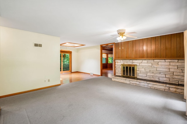 41 Colburn Dr, Poughkeepsie, NY 12603 - unfurnished living room with carpet floors, ceiling fan, wooden walls, and a stone fireplace