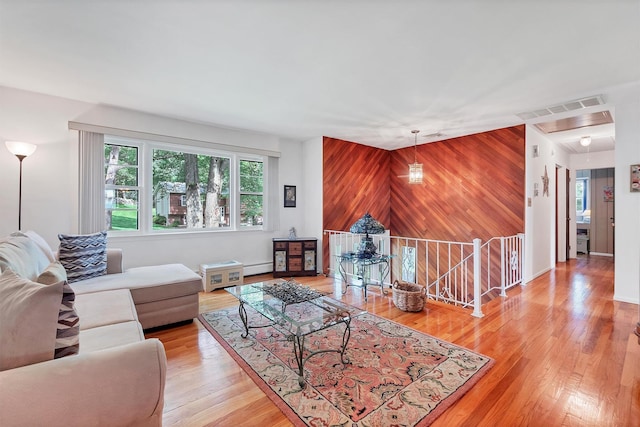 17 Woodrum Dr, Stony Point, NY 10980 - living room featuring wood walls, light wood-style floors, a baseboard radiator, and an accent wall