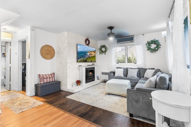 121 Thomas Ave, Bethpage, NY 11714 - living room with radiator heating unit, wood finished floors, a lit fireplace, and a wall mounted AC