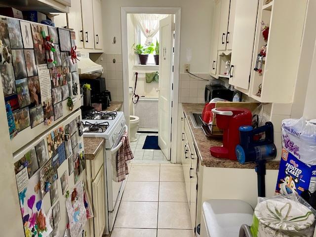 53-80 72nd Pl, Maspeth, NY 11378 - kitchen featuring white appliances, light tile patterned flooring, white cabinetry, and custom range hood