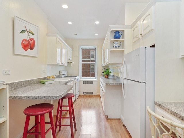 1 Midland Gdns Unit 4A, Bronxville, NY 10708 - kitchen with white appliances, radiator, light wood finished floors, a breakfast bar, and a peninsula