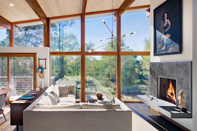 34 Old Neck Rd S, Center Moriches, NY 11934 - living room featuring floor to ceiling windows, a towering ceiling, wood finished floors, a lit fireplace, and a wood ceiling with exposed beams