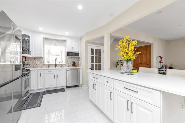 1159 129th St, College Point, NY 11356 - kitchen featuring appliances with stainless steel finishes, backsplash, light countertops, white cabinetry, and recessed lighting