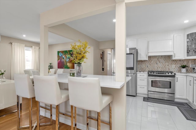 1159 129th St, College Point, NY 11356 - kitchen featuring appliances with stainless steel finishes, a kitchen breakfast bar, white cabinets, light countertops, and recessed lighting