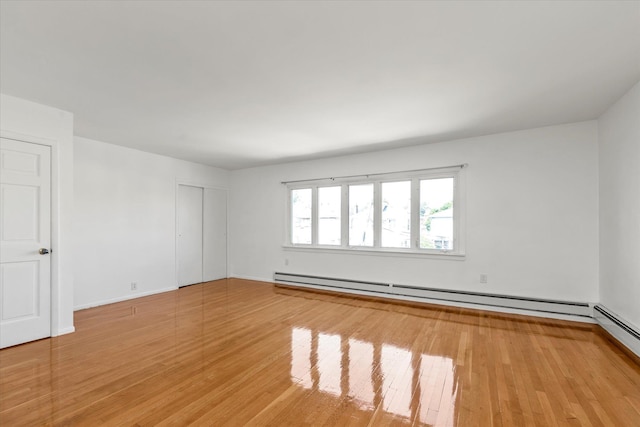 1159 129th St, College Point, NY 11356 - empty room with a baseboard heating unit and light wood-style flooring