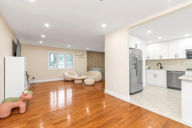 27 Heron Ln, Commack, NY 11725 - kitchen featuring stainless steel appliances, open floor plan, light countertops, light wood-style floors, and white cabinetry