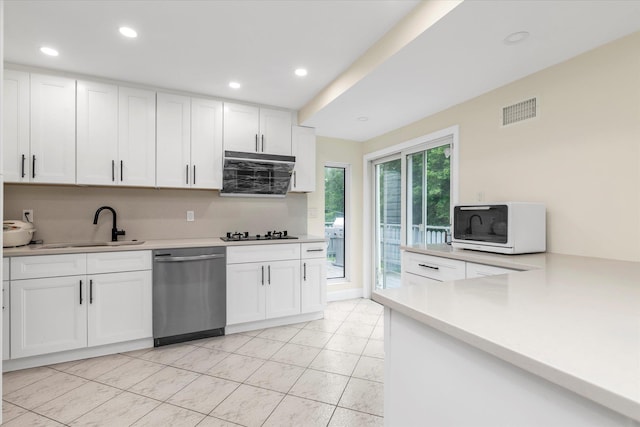 27 Heron Ln, Commack, NY 11725 - kitchen with stainless steel dishwasher, black stovetop, white microwave, white cabinets, and light countertops