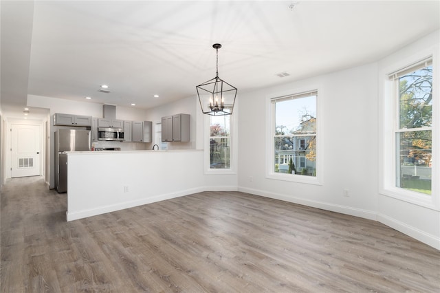 22 Forbus St, Poughkeepsie, NY 12601 - kitchen with gray cabinets, stainless steel microwave, freestanding refrigerator, wood finished floors, and light countertops