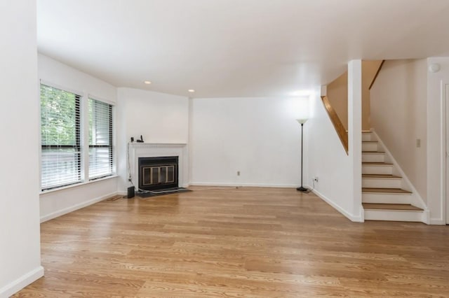 175 Horseshoe Cir, Ossining, NY 10562 - unfurnished living room featuring stairs, light wood-style floors, a fireplace with flush hearth, and recessed lighting