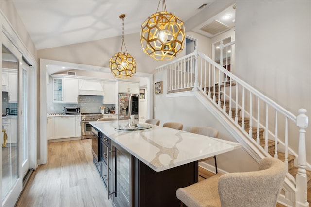 9 Elaine Pl, Plainview, NY 11803 - kitchen featuring appliances with stainless steel finishes, white cabinetry, a breakfast bar, tasteful backsplash, and beverage cooler