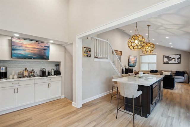 9 Elaine Pl, Plainview, NY 11803 - kitchen with high vaulted ceiling, light wood-style flooring, decorative backsplash, a kitchen breakfast bar, and recessed lighting