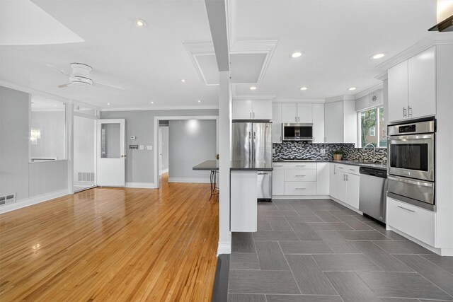 7 Fuller Rd, Ossining, NY 10562 - kitchen with appliances with stainless steel finishes, a warming drawer, crown molding, dark countertops, and white cabinetry