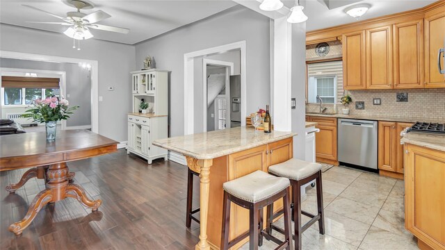 17111 Bagley Ave, Flushing, NY 11358 - kitchen with dishwasher, tasteful backsplash, a breakfast bar, a ceiling fan, and light stone counters