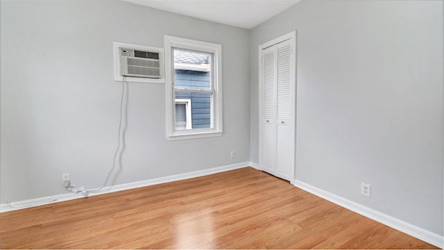17111 Bagley Ave, Flushing, NY 11358 - unfurnished bedroom featuring light wood finished floors, a closet, and an AC wall unit
