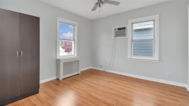 17111 Bagley Ave, Flushing, NY 11358 - unfurnished bedroom with radiator, multiple windows, light wood-style flooring, and an AC wall unit
