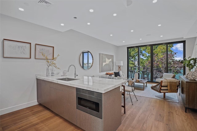 21-31 Shore Blvd Unit 3D, Astoria, NY 11105 - kitchen featuring stainless steel microwave, a peninsula, open floor plan, recessed lighting, and light wood finished floors