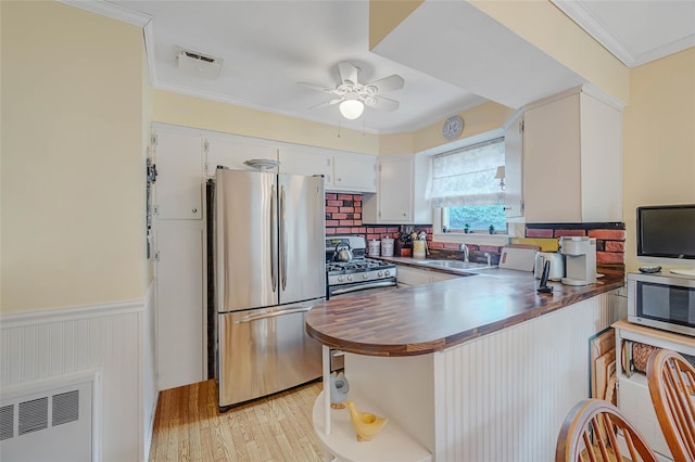 15 Peony Ln, Commack, NY 11725 - kitchen with stainless steel appliances, a ceiling fan, light wood-style floors, a peninsula, and ornamental molding