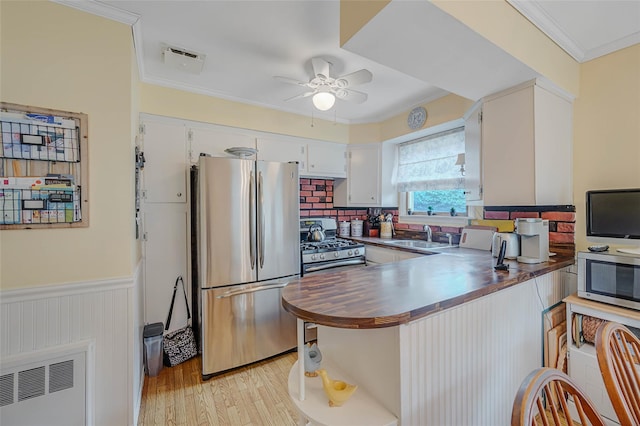 15 Peony Ln, Commack, NY 11725 - kitchen with stainless steel appliances, a ceiling fan, ornamental molding, a peninsula, and a wainscoted wall