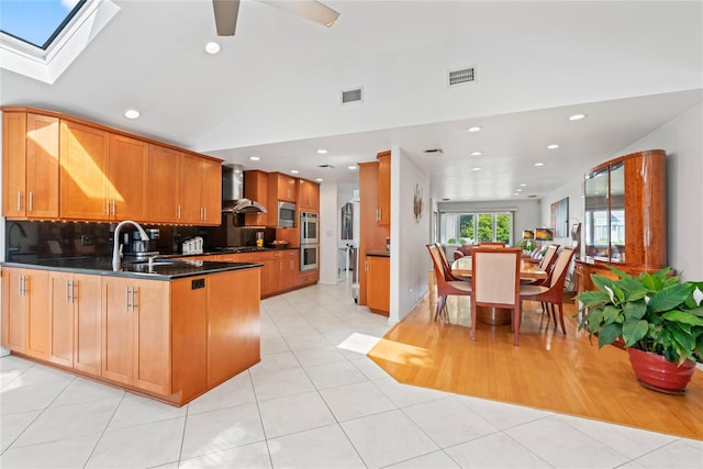 128 Seaman Rd, Jericho, NY 11753 - kitchen featuring wall chimney exhaust hood, lofted ceiling, a peninsula, appliances with stainless steel finishes, and dark countertops