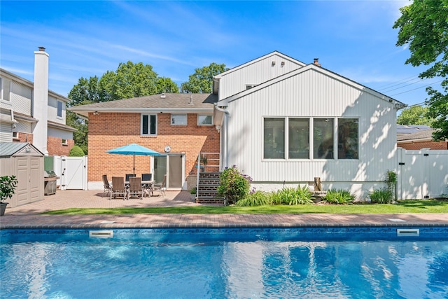 128 Seaman Rd, Jericho, NY 11753 - rear view of house with a gate, a patio area, a storage unit, brick siding, and a chimney