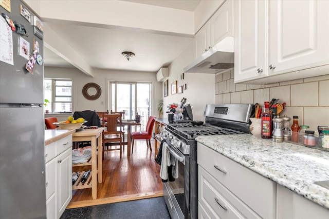 69-28 43rd Ave, Woodside, NY 11377 - kitchen featuring stainless steel appliances, under cabinet range hood, white cabinetry, tasteful backsplash, and a wall mounted air conditioner