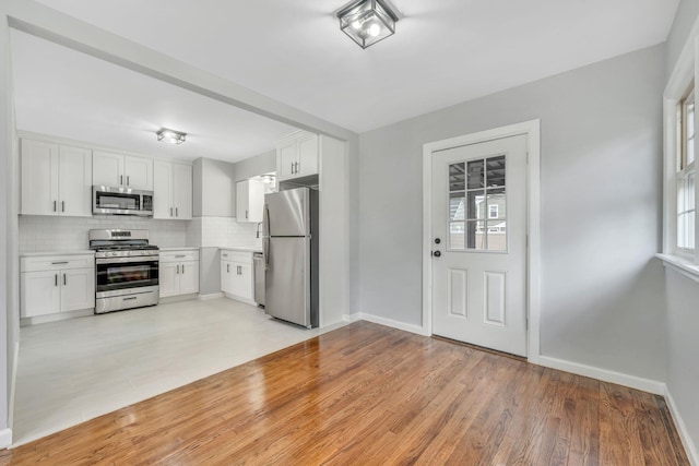 139 Jean Ave, Hempstead, NY 11550 - kitchen featuring stainless steel appliances, tasteful backsplash, white cabinets, light countertops, and light wood-type flooring