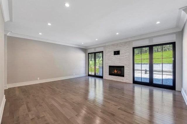 589 Old Bridge Rd, Northport, NY 11768 - unfurnished living room with ornamental molding, wood finished floors, recessed lighting, and a stone fireplace
