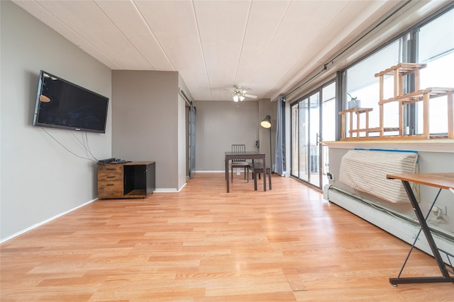 92-29 Queens Blvd Unit 14B, Rego Park, NY 11374 - dining area with a baseboard heating unit, light wood-style floors, a barn door, and a ceiling fan