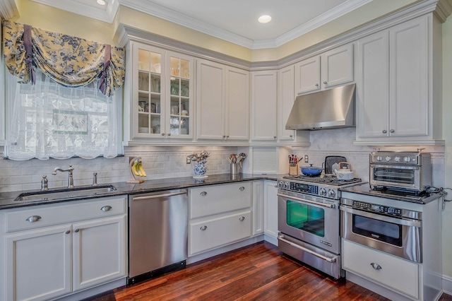 33 S Bay Ave, Amityville, NY 11701 - kitchen featuring appliances with stainless steel finishes, under cabinet range hood, ornamental molding, dark wood-type flooring, and tasteful backsplash