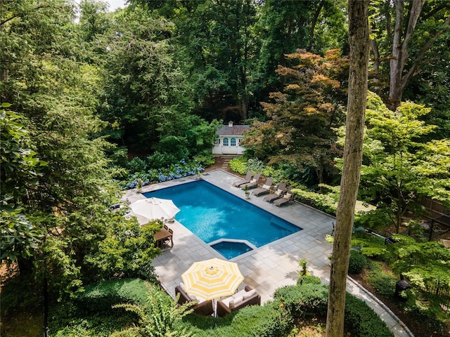 15 Glen Pk Rd, Purchase, NY 10577 - view of pool with an outbuilding, a pool with connected hot tub, a view of trees, a deck, and a patio area