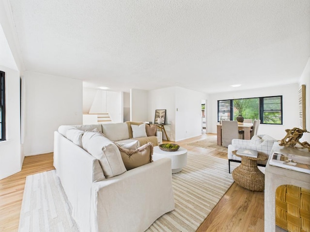 811 Bellmore Ave, East Meadow, NY 11554 - living room with stairs, light wood-style floors, and a textured ceiling